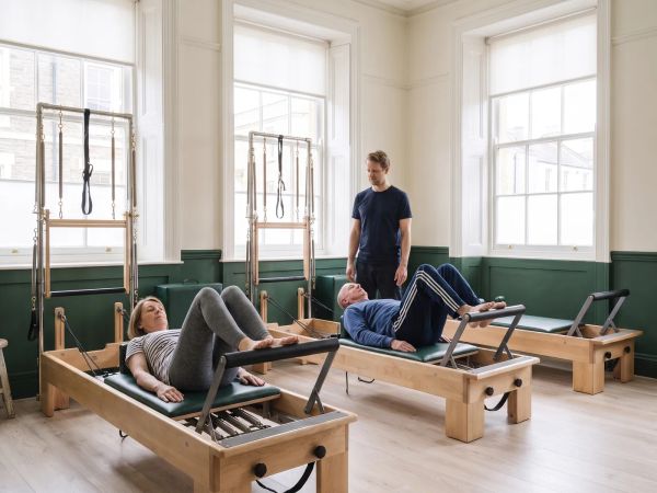 Theo supervises a small reformer class in daylight.