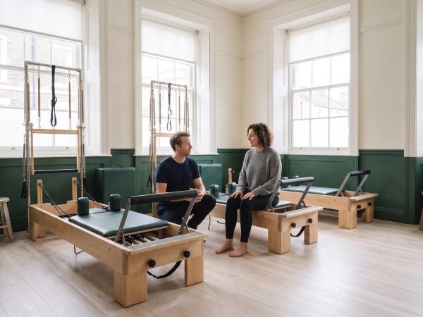 An instructor talks a client through a private session on a reformer.
